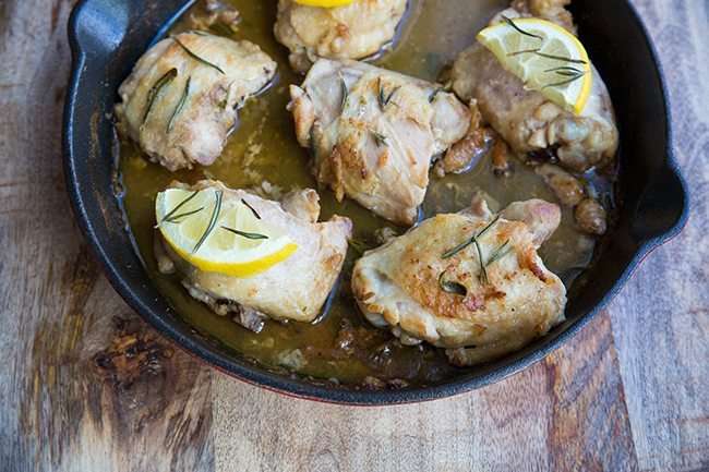 Oven Baked Chicken Thighs topped with Lemon and Rosemary in an Oven Safe Skillet